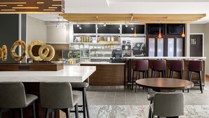 A modern kitchen with a central island, bar stools, and a seating area with a round table.
