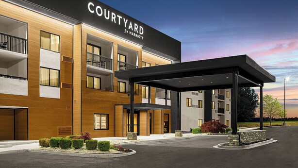 A modern Courtyard by Marriott hotel with a covered entrance, multiple balconies, and a landscaped entrance area.