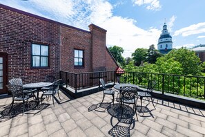 A brick building with a balcony featuring outdoor seating.
