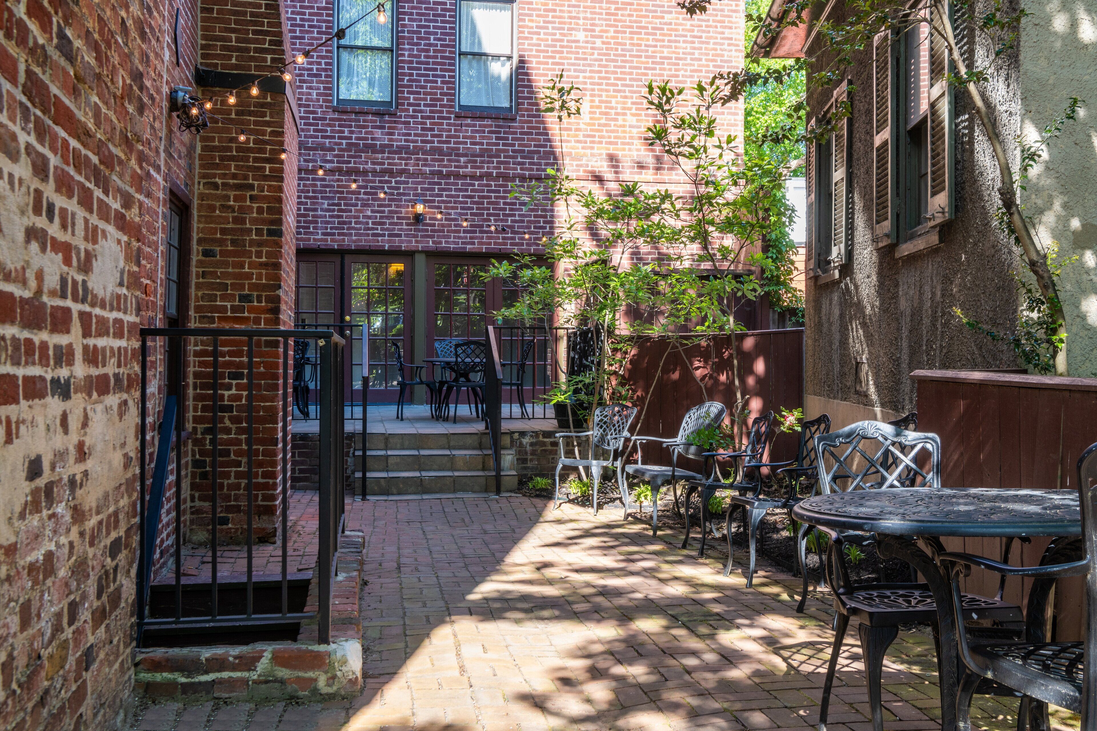 A brick building with a patio area featuring outdoor seating and a staircase leading to an entrance.