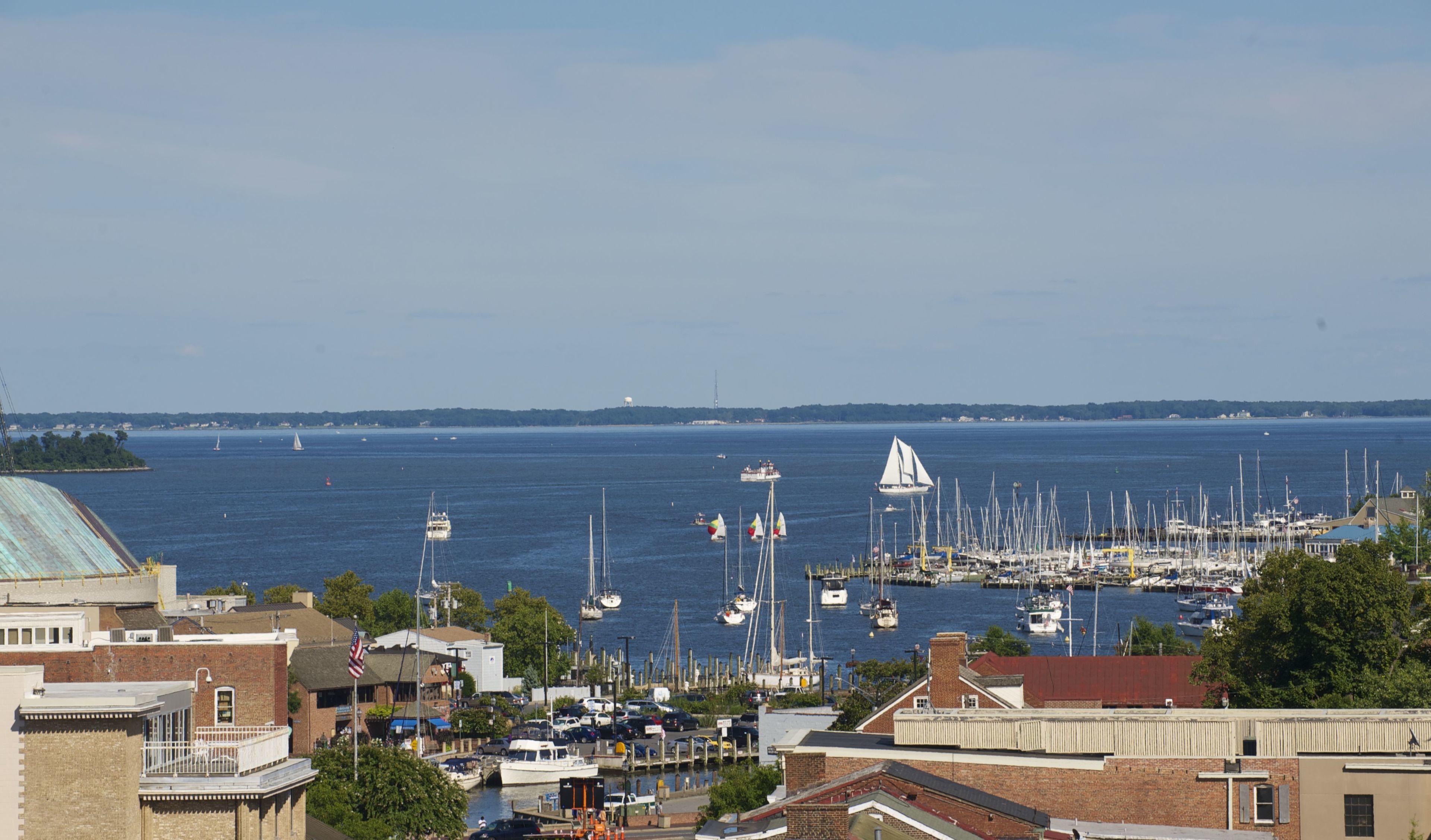A marina with multiple boats docked, a clear view of the water, and buildings in the foreground.