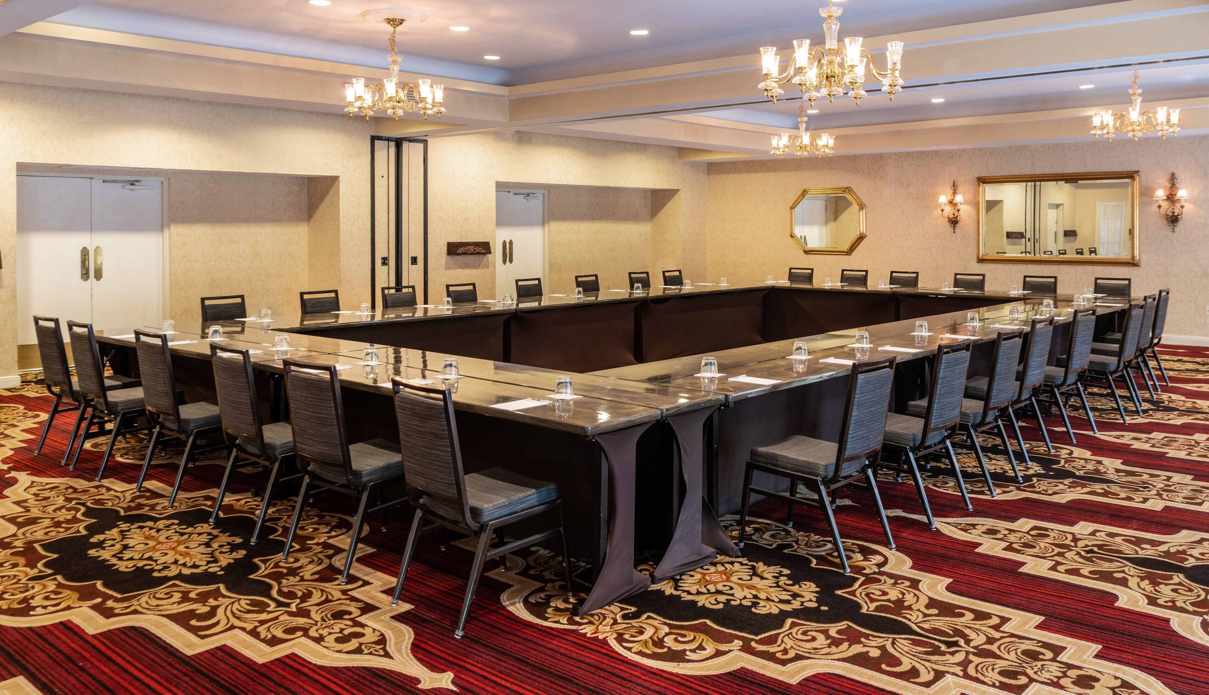 A conference room with a long table, chairs, and a carpeted floor.