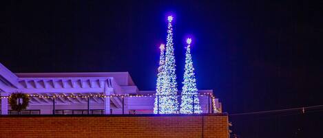 Ein Gebäude mit großen Fenstern, die Weihnachtsschmuck zeigen, einer Backsteinfassade und einem Spiegelbild im vorderen Wasser.