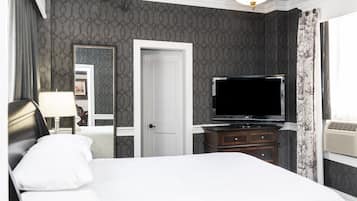 Una habitación de hotel con una cama, televisión, cómoda y espejo.