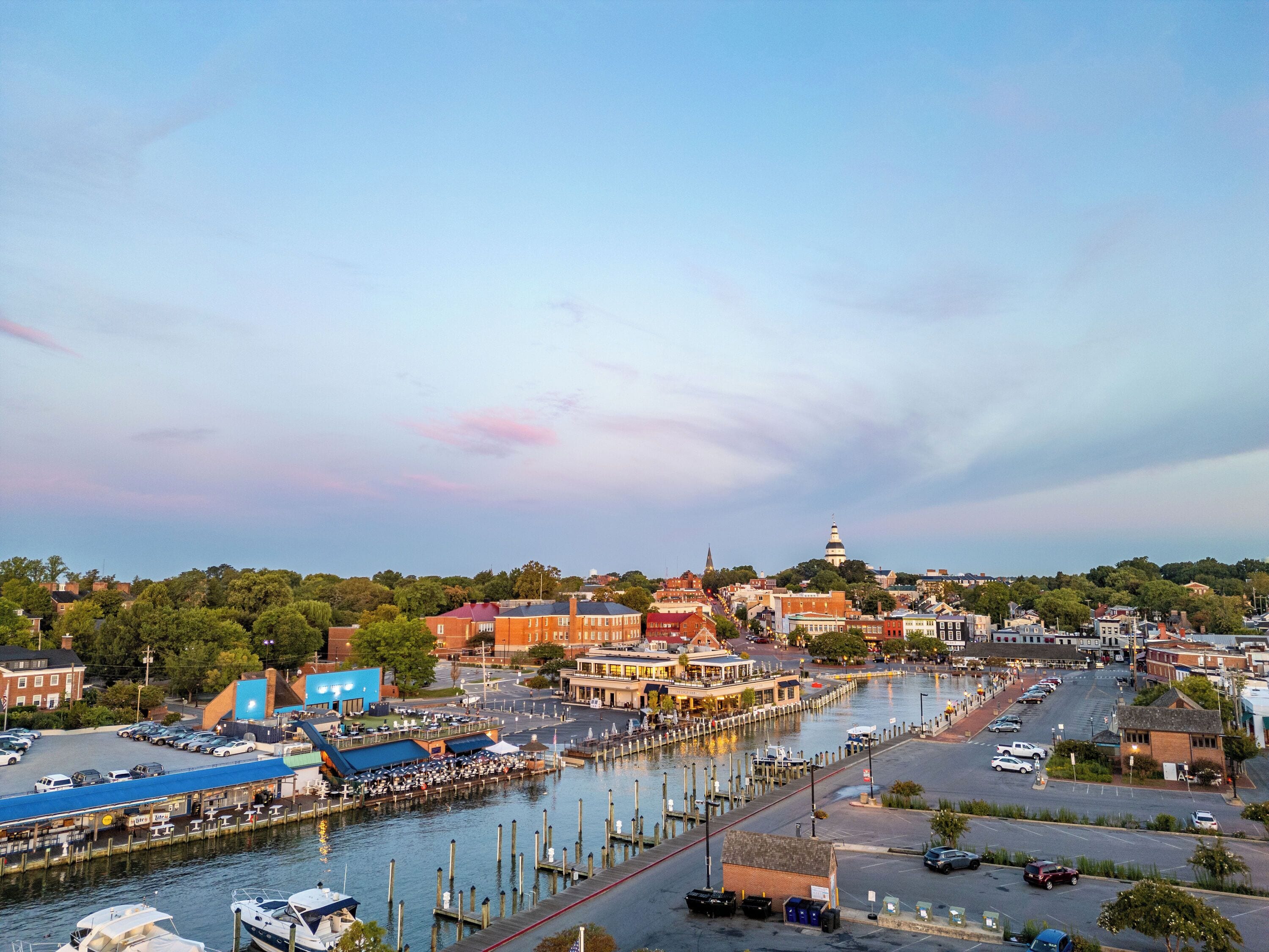 A waterfront cityscape with a prominent church steeple, a marina with boats, and a mix of commercial and residential buildings.