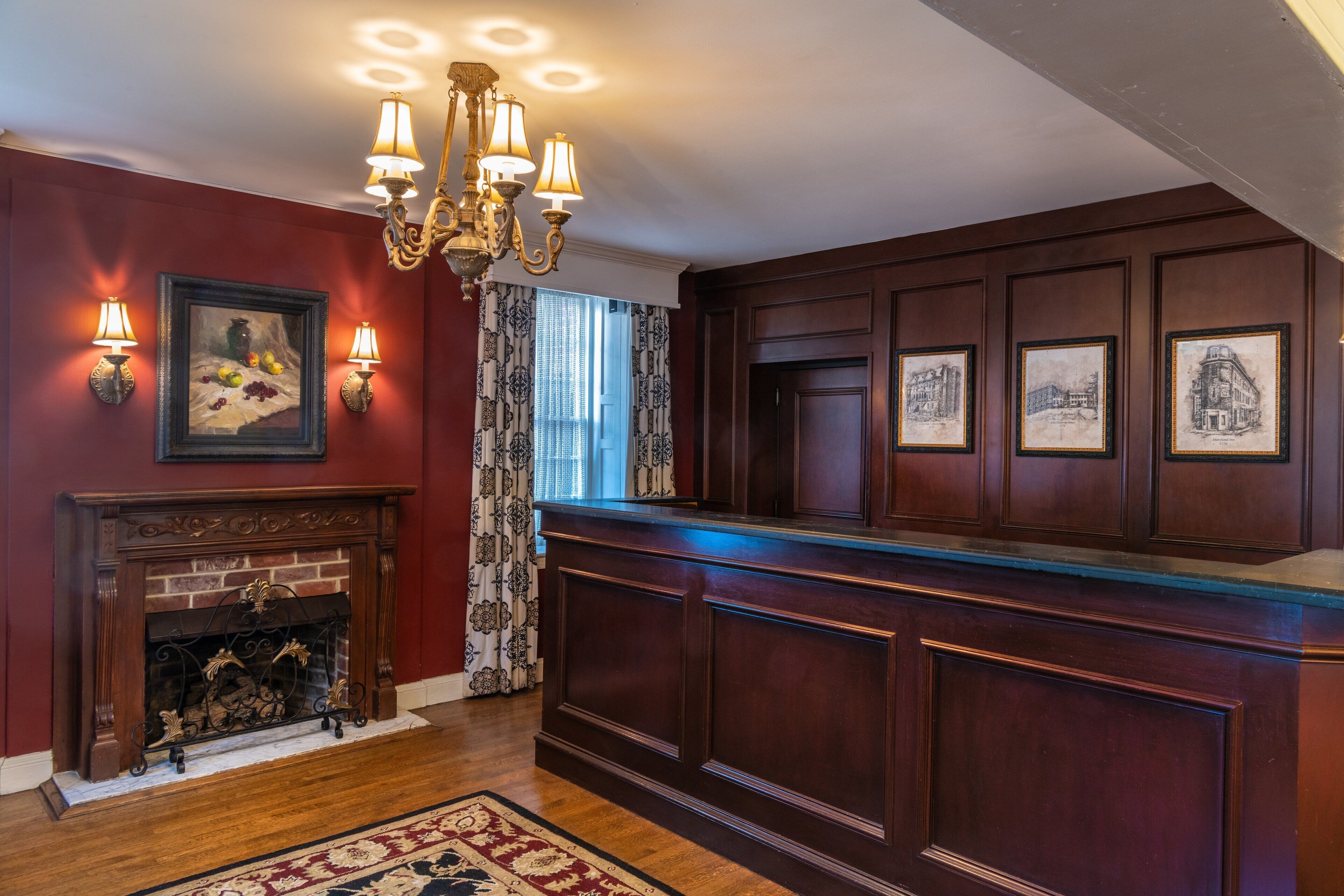 A room with a fireplace, wooden paneling, and framed artwork on the walls.