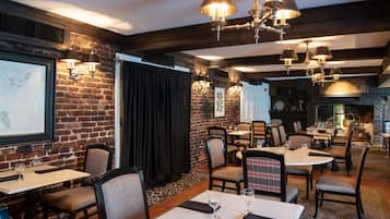 A restaurant with brick walls, multiple tables and chairs, and hanging lamps.