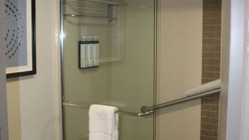 A modern bathroom with a glass-enclosed shower, a toilet, and a framed artwork on the wall.