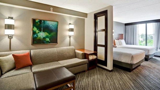 A hotel room with a sofa, a small table, two beds, and a painting on the wall. - Hyatt Place Baltimore/BWI Airport (Linthicum Heights)