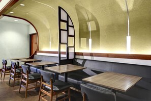 Un interior de restaurante con asientos tipo cabina, mesas de madera y un techo curvo.