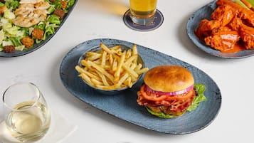 A meal with a burger, fries, salad, and wings on separate plates.