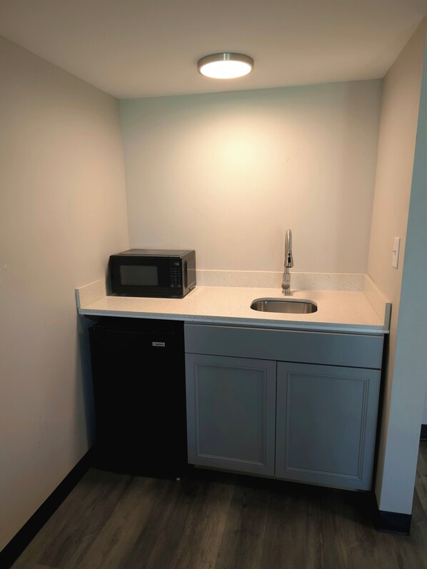 A compact kitchenette with a microwave, sink, and dishwasher.