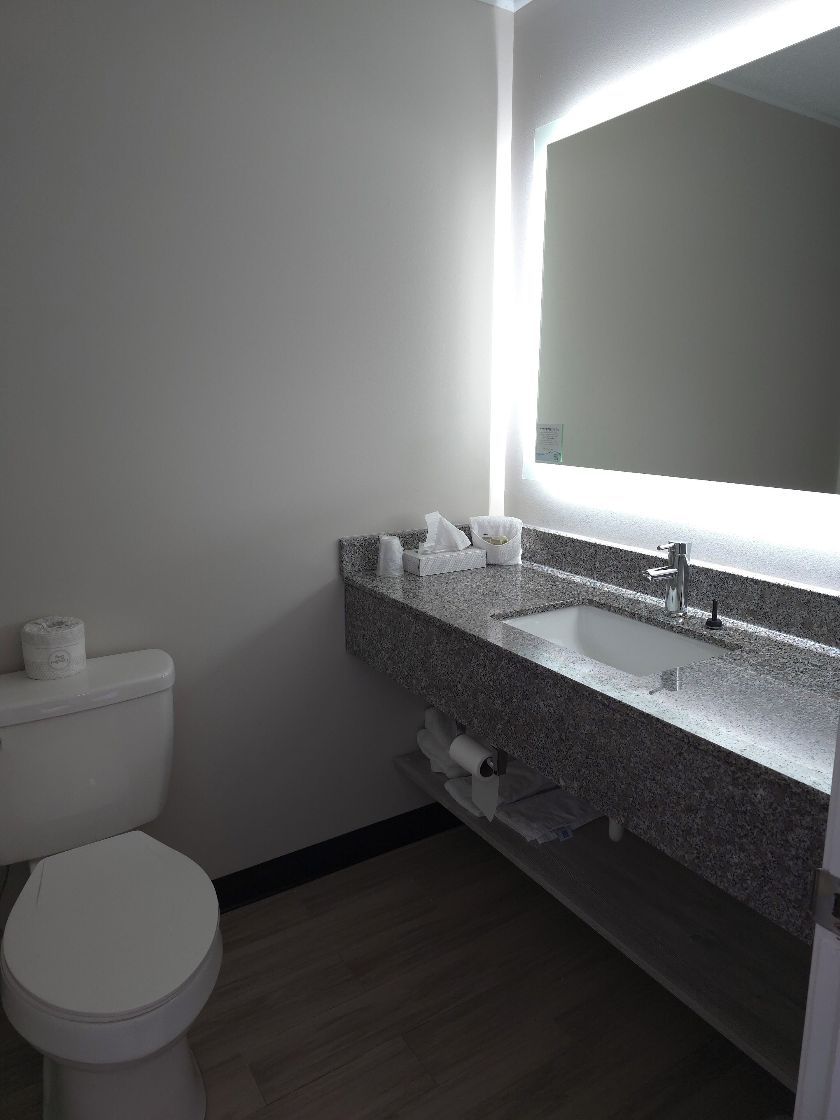 A bathroom with a toilet, sink, and mirror.