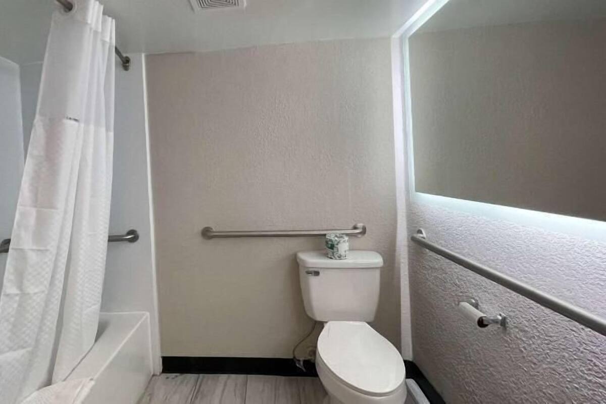 A small bathroom with a toilet, a shower curtain, and a grab bar.