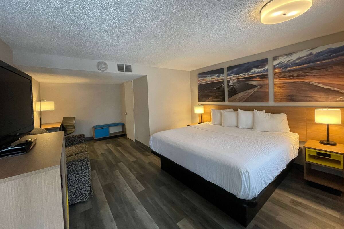 A hotel room with a large bed, a television, a desk, and a seating area.