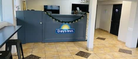 A reception area with a Days Inn sign, a counter, and a seating area with chairs.