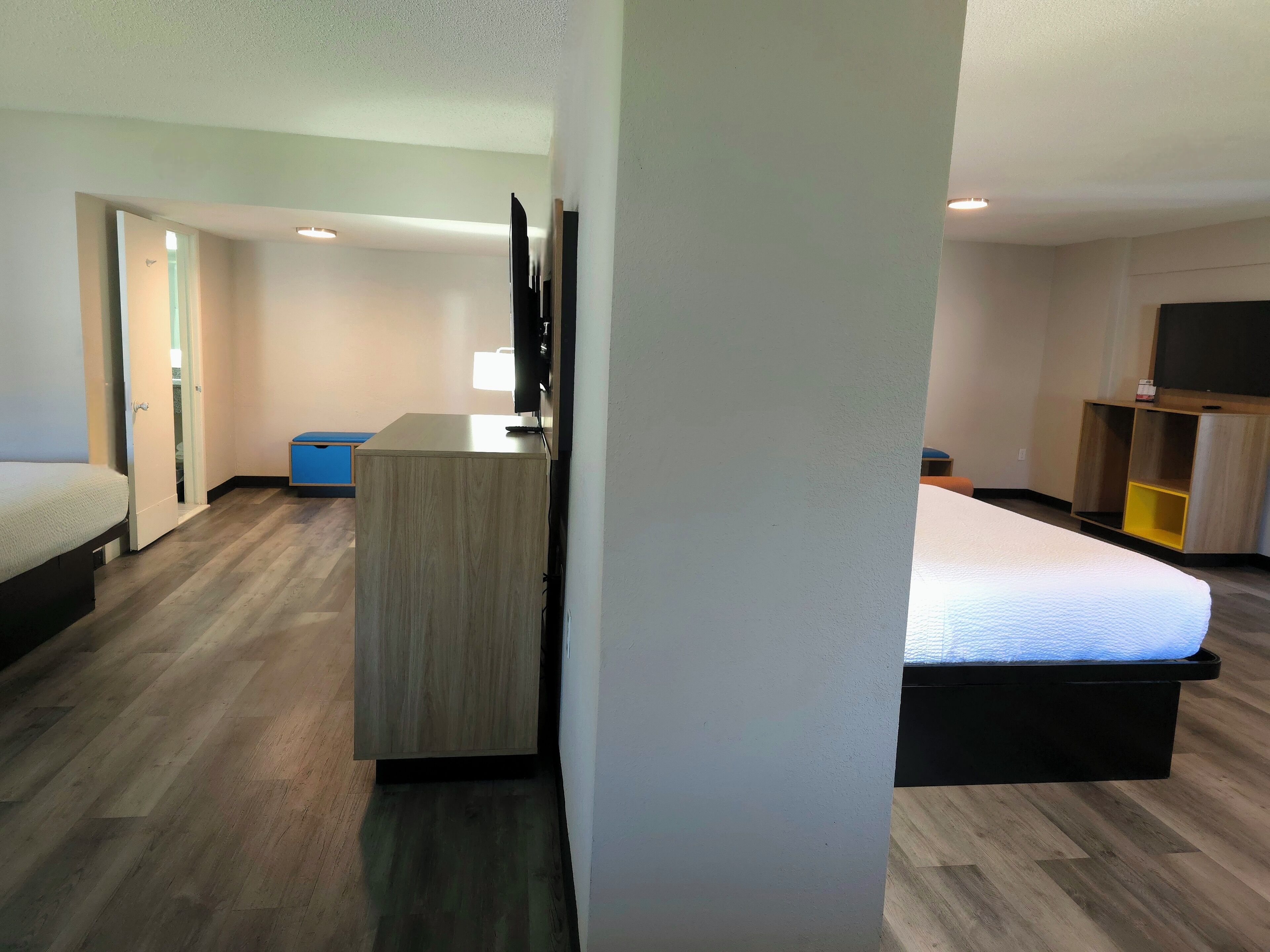 A hotel room with a bed, a desk, a television, and a wardrobe.