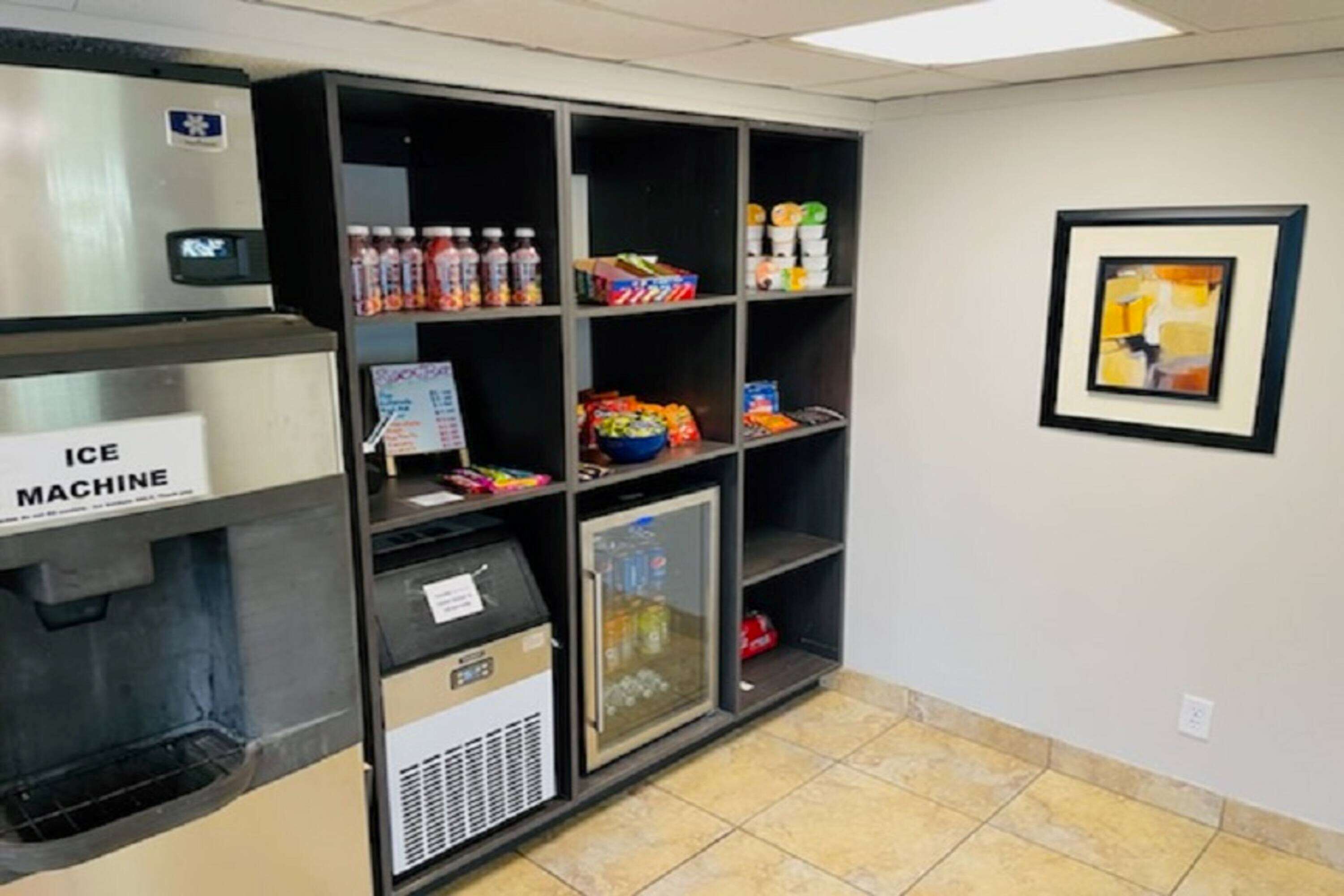 A vending machine area with an ice machine, shelves stocked with beverages and snacks, and a refrigerator.