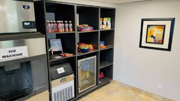 A vending machine area with an ice machine, shelves stocked with beverages and snacks, and a refrigerator.