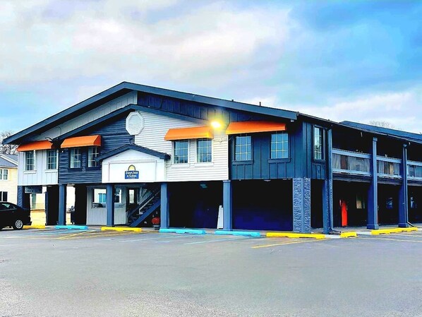 A multi-story building with a Days Inn sign, a parking garage, and a visible staircase leading to the entrance. - Days Inn & Suites by Wyndham Port Huron (Port Huron)
