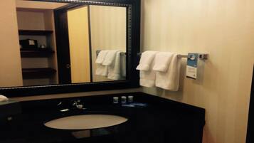 A bathroom with a large mirror, a black sink, and two white towels hanging on a towel rack.