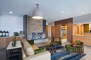 A modern hotel lobby with a stone fireplace, seating area, and a reception desk. - Fairfield Inn By Marriott Kansas City Airport (Kansas City)