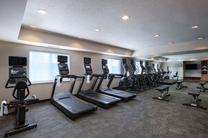 A gym with multiple treadmills, exercise bikes, and a mirrored wall.