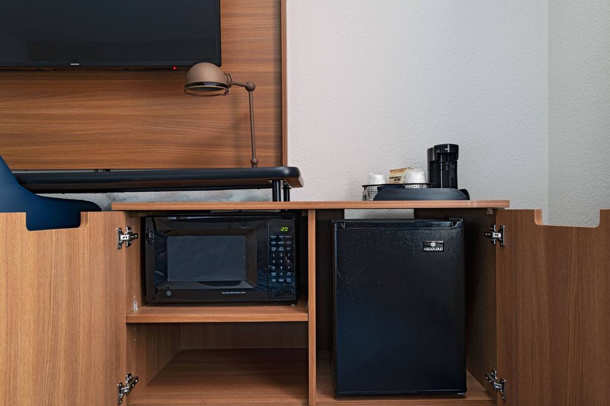 A compact kitchenette with a microwave, refrigerator, and coffee maker.