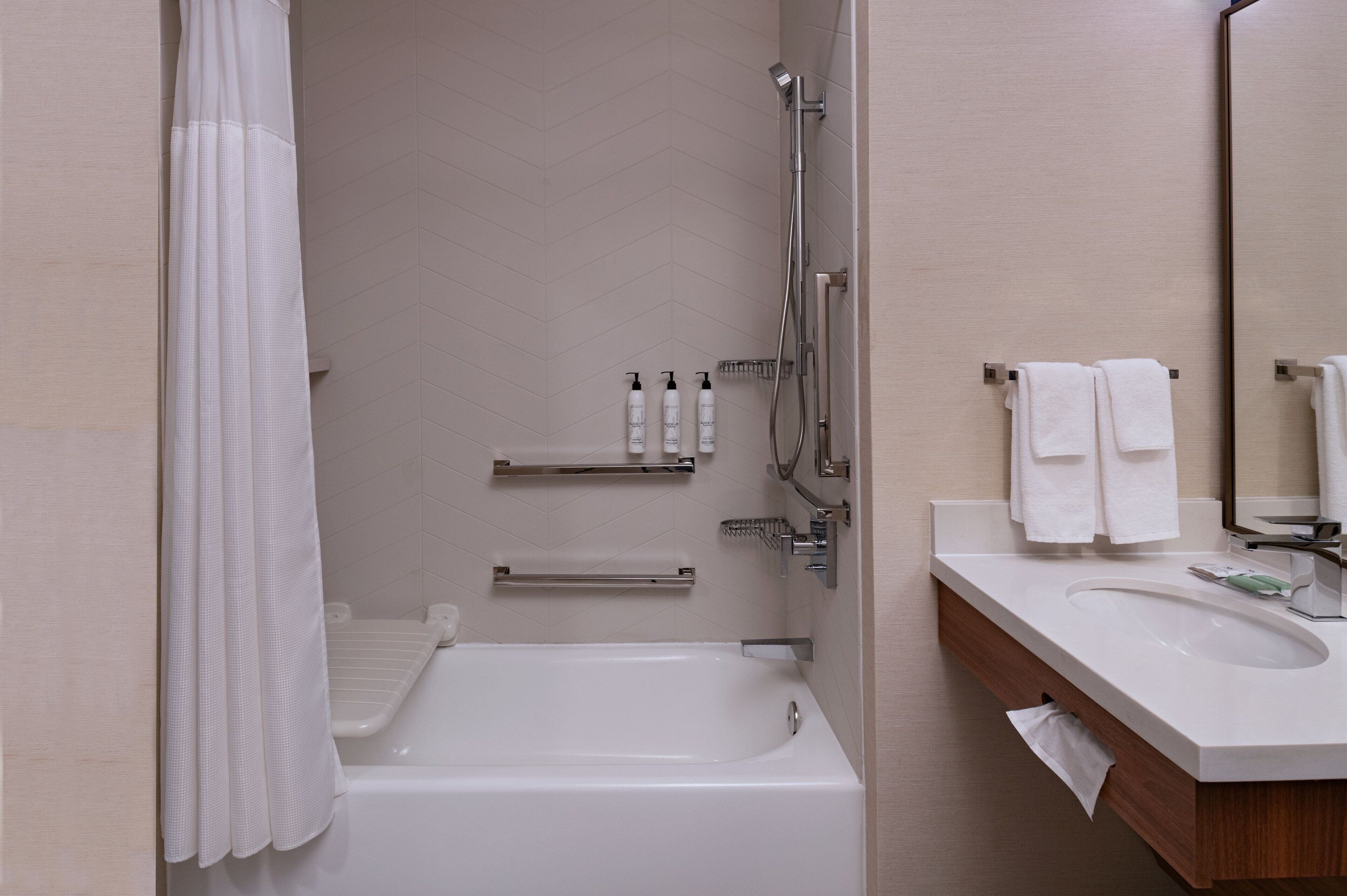 A modern bathroom with a bathtub, shower, and sink.