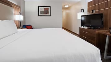 A hotel room with a large bed, a desk with a flat-screen TV, a chair, and a wall-mounted TV.
