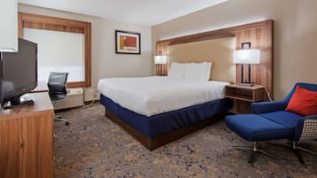 Ein Hotelzimmer mit Bett, Schreibtisch mit Fernseher, Stuhl und Nachttisch mit Lampen.