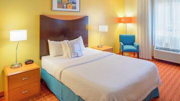 A hotel room with a large bed, two bedside tables, a chair, a window with curtains, and a wall-mounted picture.