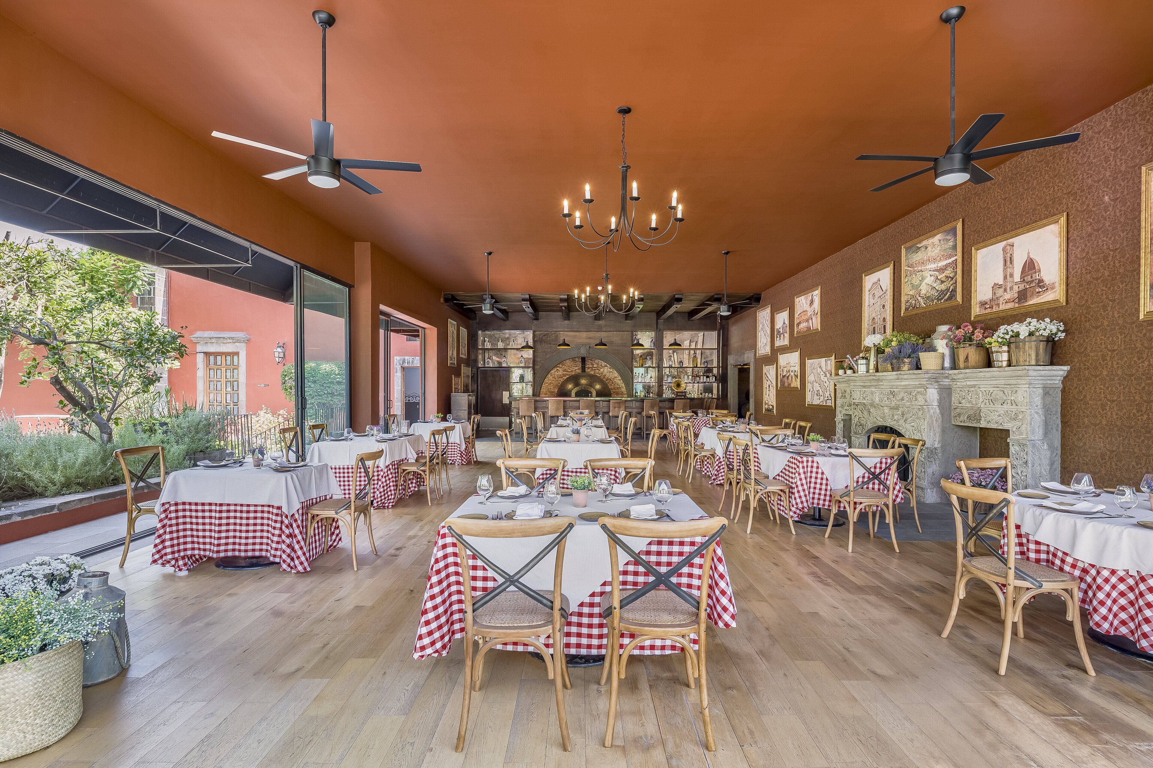 Un comedor amplio con varias mesas y sillas, ventiladores de techo y una chimenea.
