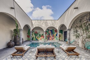 Relax by the serene pool surrounded by a vibrant mural and lush greenery.