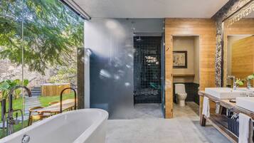Un baño moderno con bañera, tocador de madera y un espejo grande.
