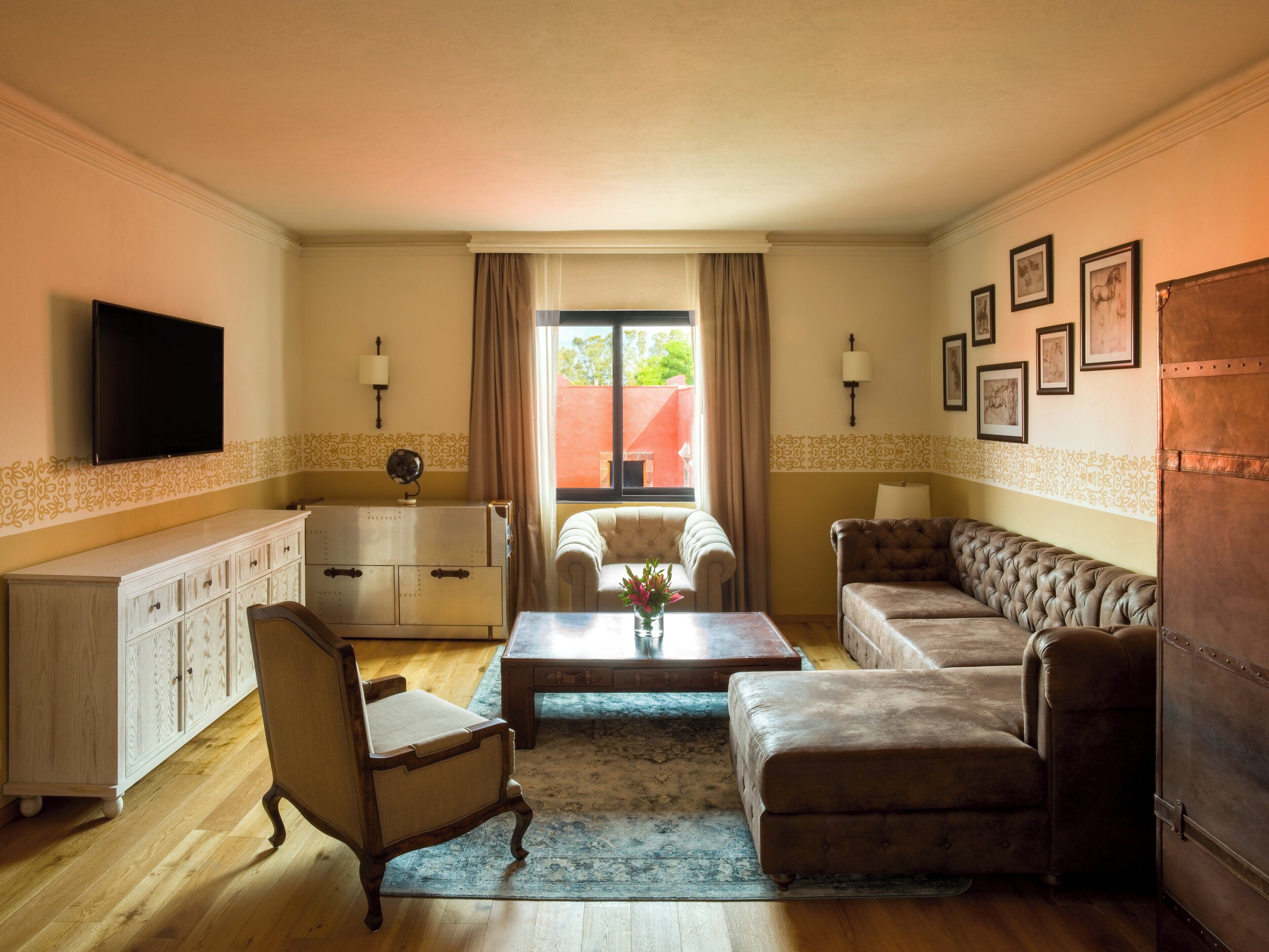 A living room with a sofa, armchair, and a television mounted on the wall.
