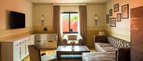 A living room with a sofa, armchair, and a television mounted on the wall.