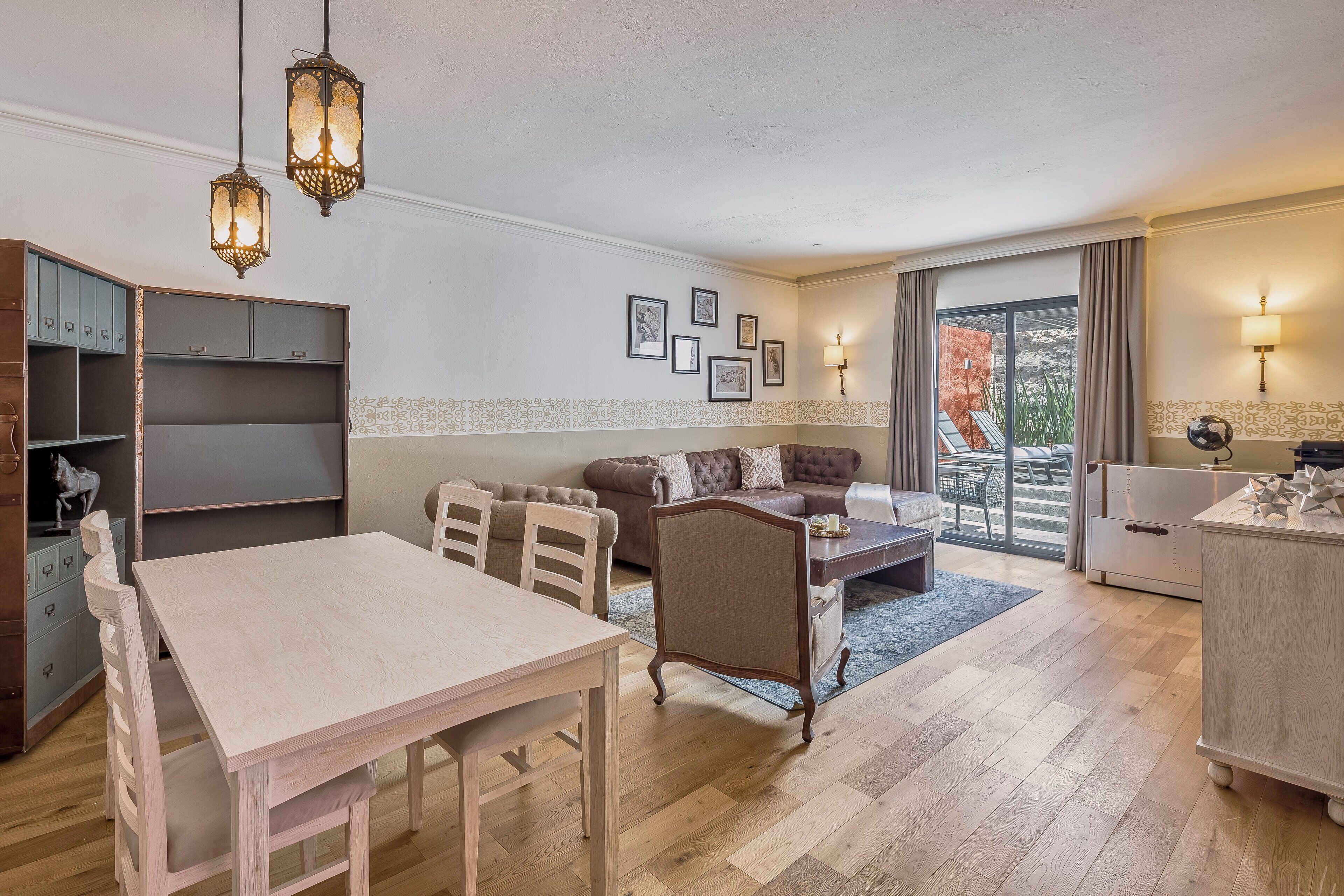 A spacious living area with a dining table, a sofa, and a balcony with a view.
