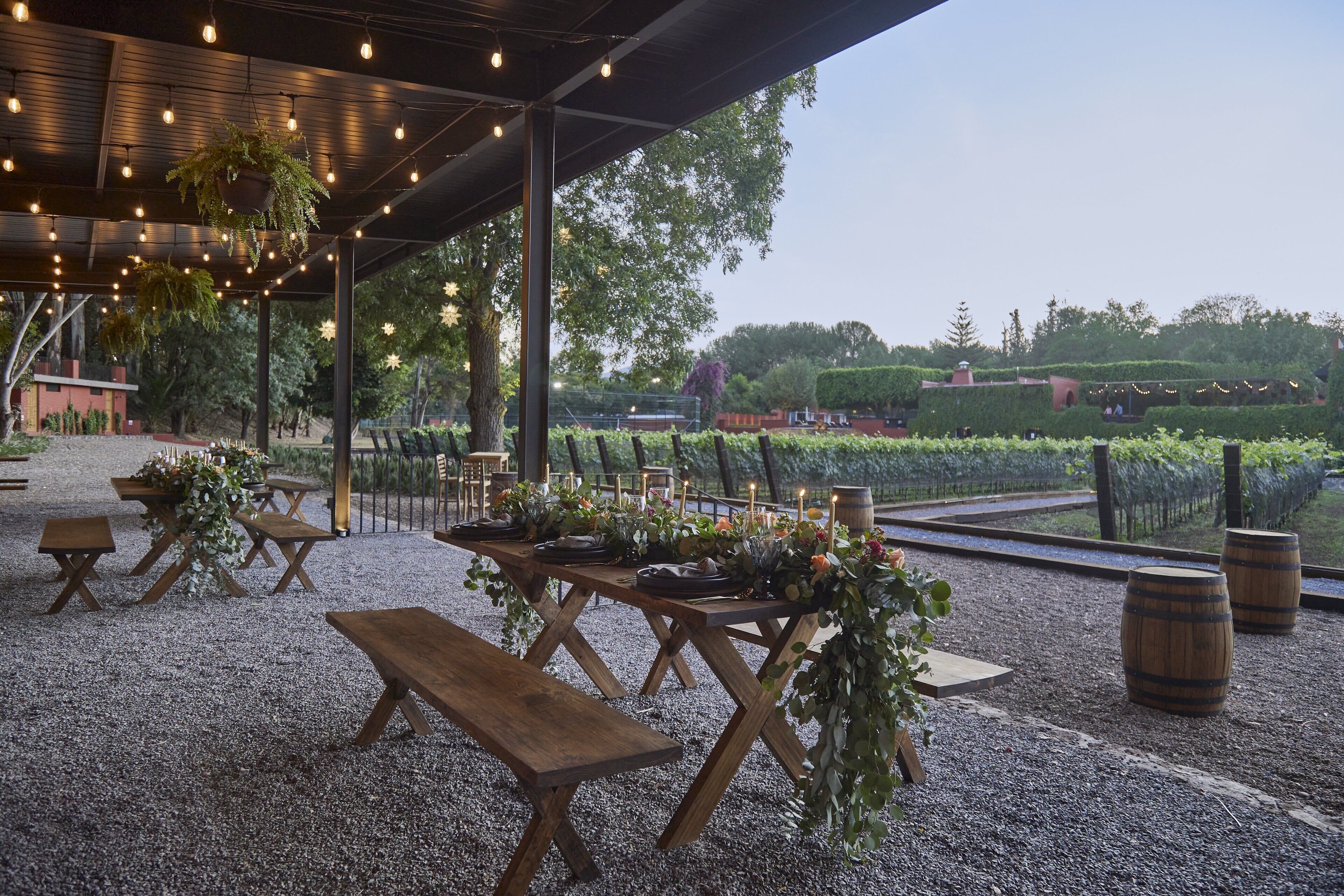 Un área de comedor al aire libre con mesas y bancos de madera, rodeada de grava.