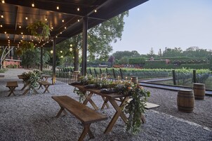 Un área de comedor al aire libre con mesas y bancos de madera, rodeada de grava.