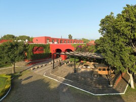 Un patio con un edificio rojo, una zona de estar cubierta y un carrito antiguo.