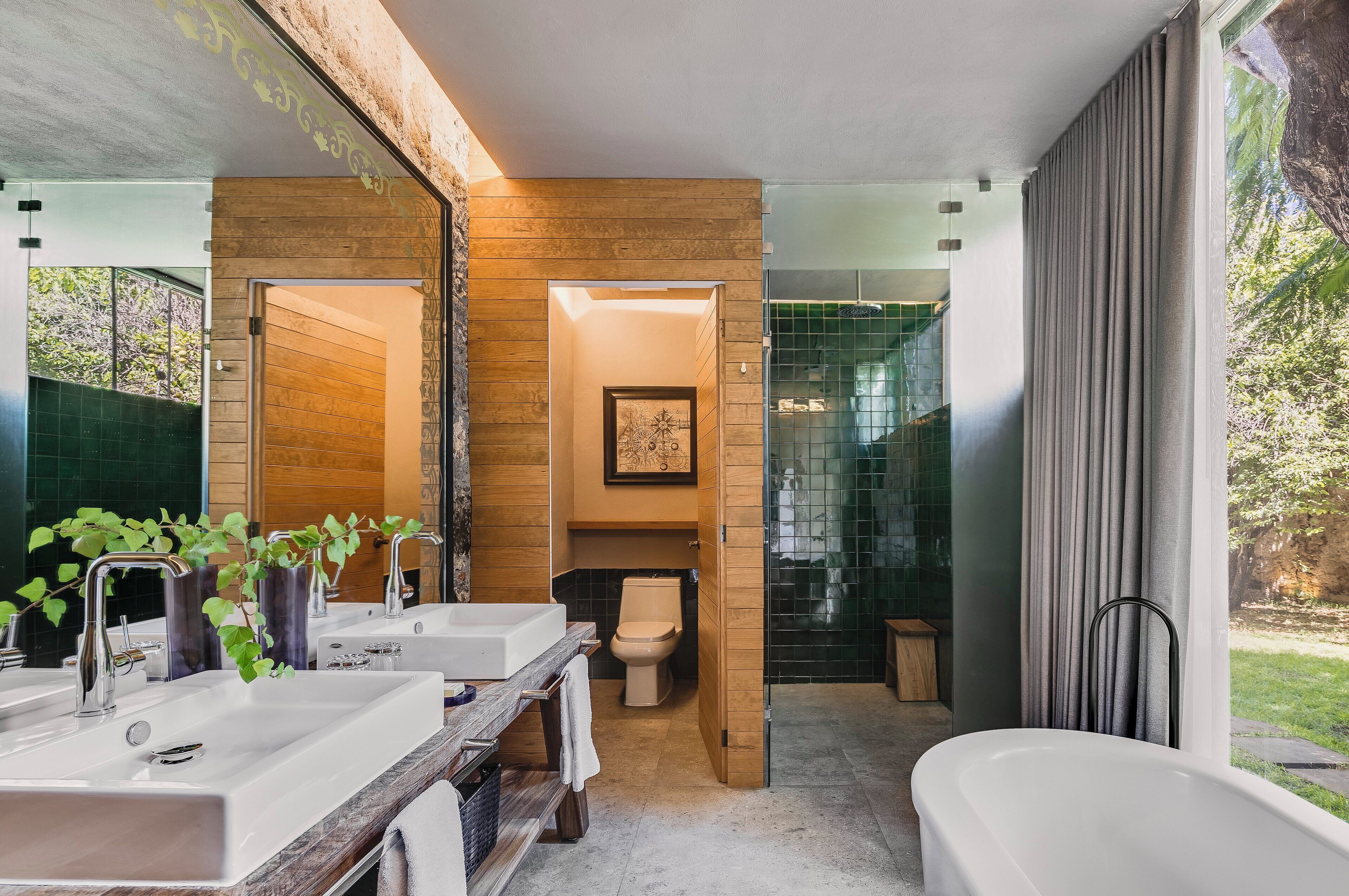 A modern bathroom with a large mirror, two sinks, a toilet, and a bathtub.