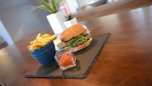 Una mesa con una hamburguesa y papas fritas sobre un plato de pizarra negra.