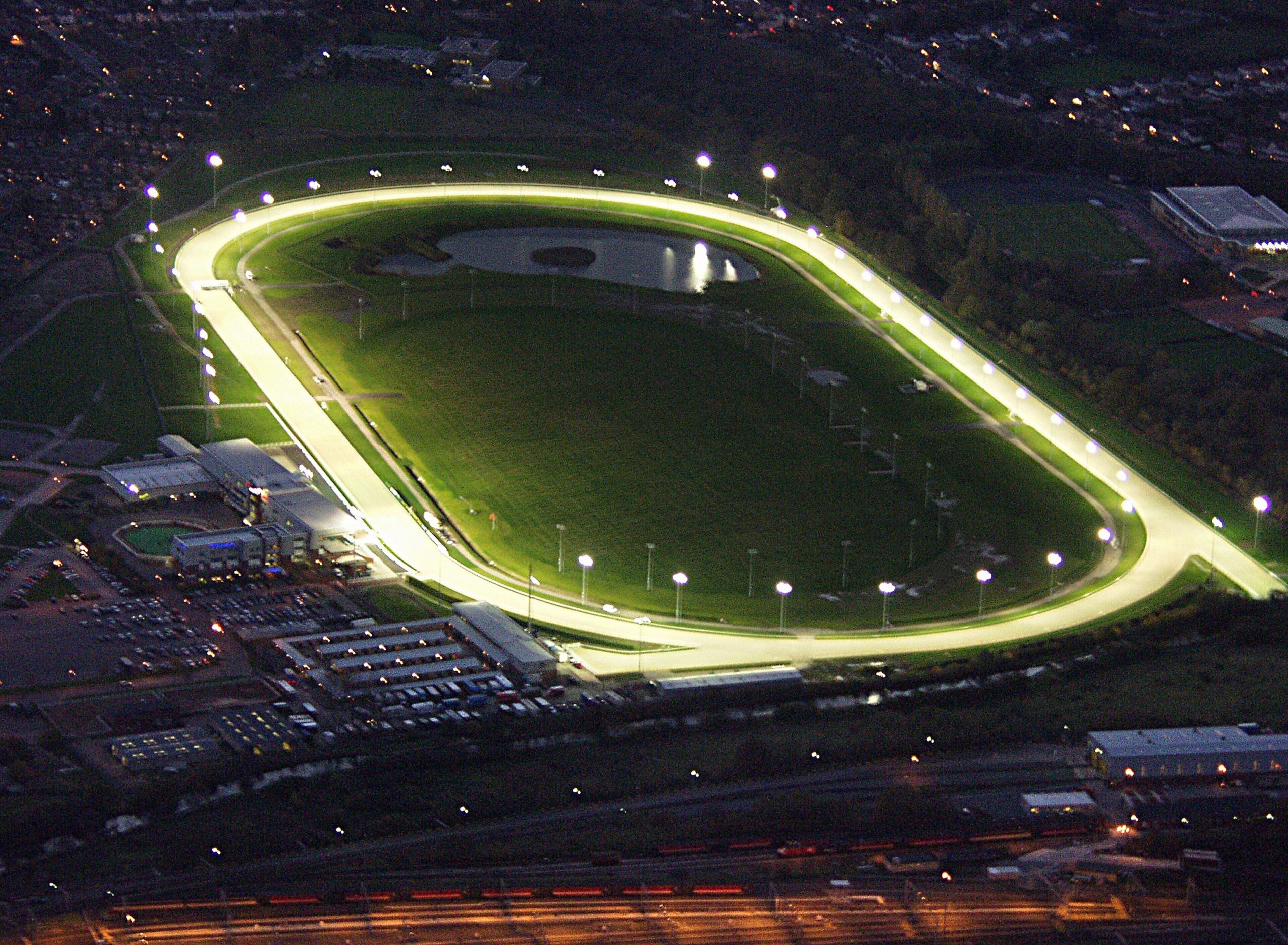 Vista aérea de un estadio con pista de atletismo, zonas de asientos y edificios circundantes.