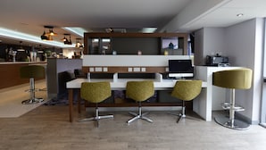 Un área de bar moderna con mostrador, asientos y una pantalla de televisión.