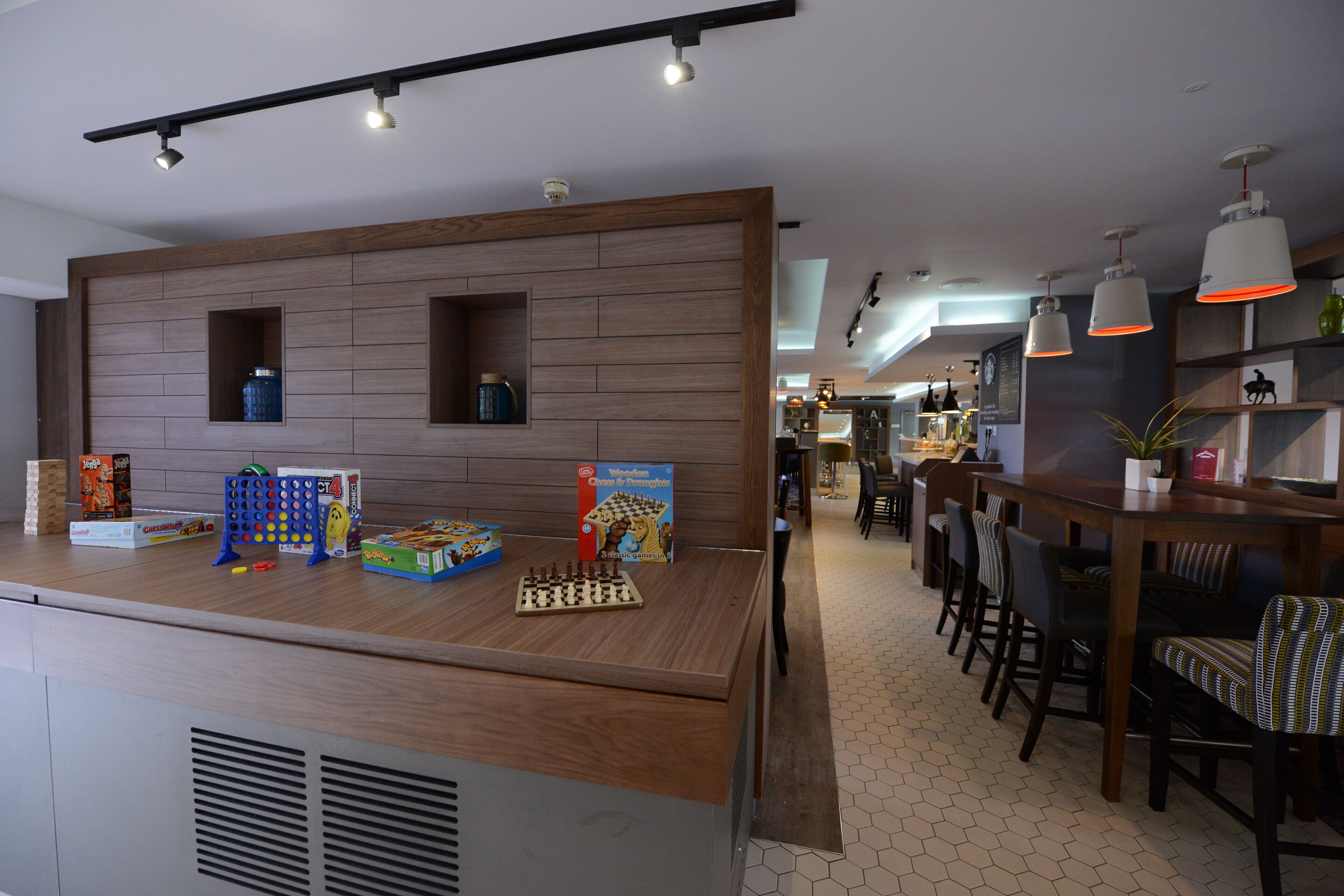 A modern kitchen with wooden accents, a dining area with bar stools, and various board games on the counter.