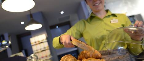 Una persona sirve comida, concretamente pasteles, en un ambiente interior bien iluminado con lámparas modernas.