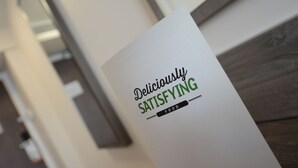 Un cartel con el texto 'Comida deliciosamente satisfactoria' en un ambiente interior moderno.