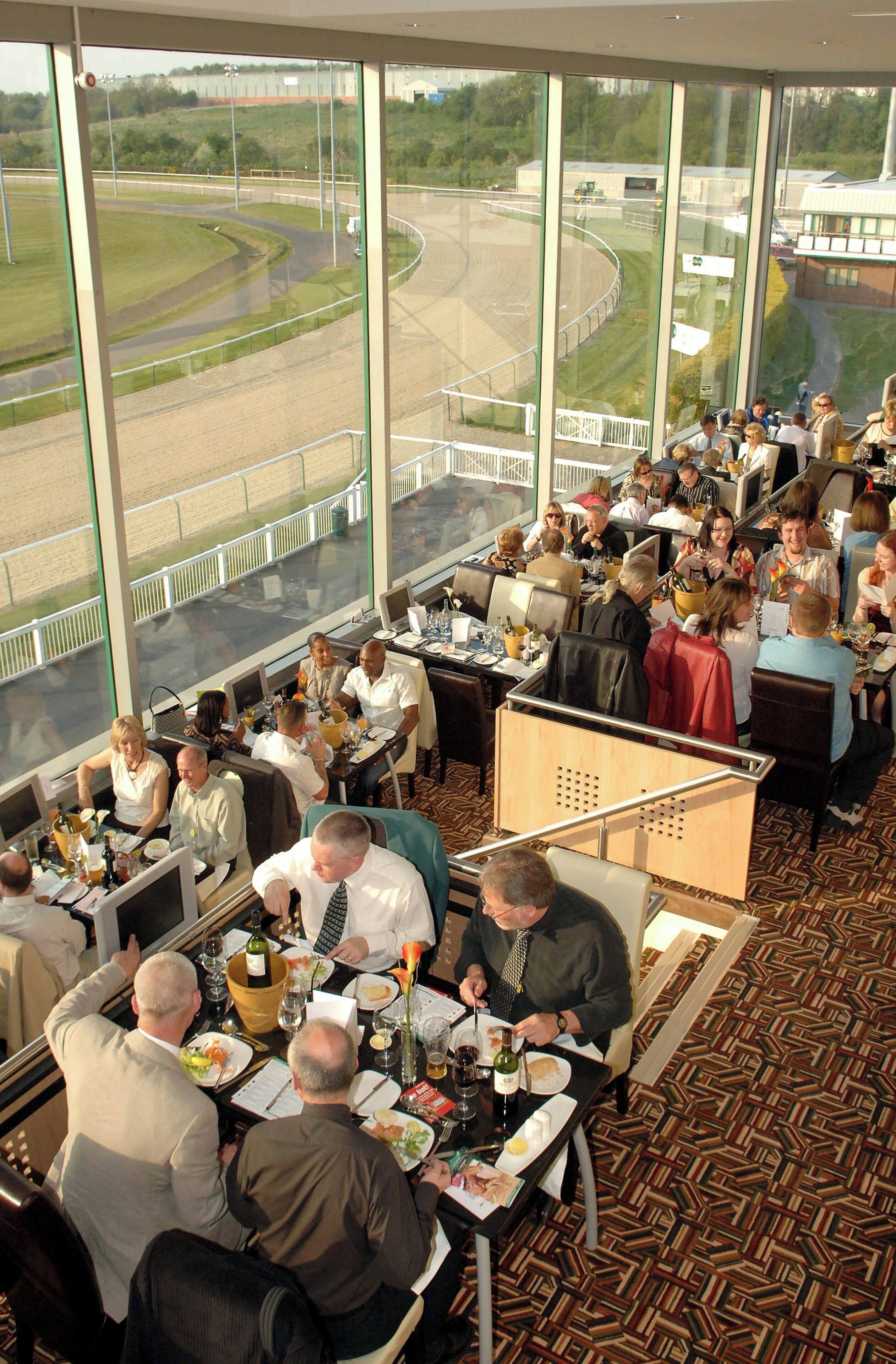 A restaurant with large windows offering a view of a racetrack.