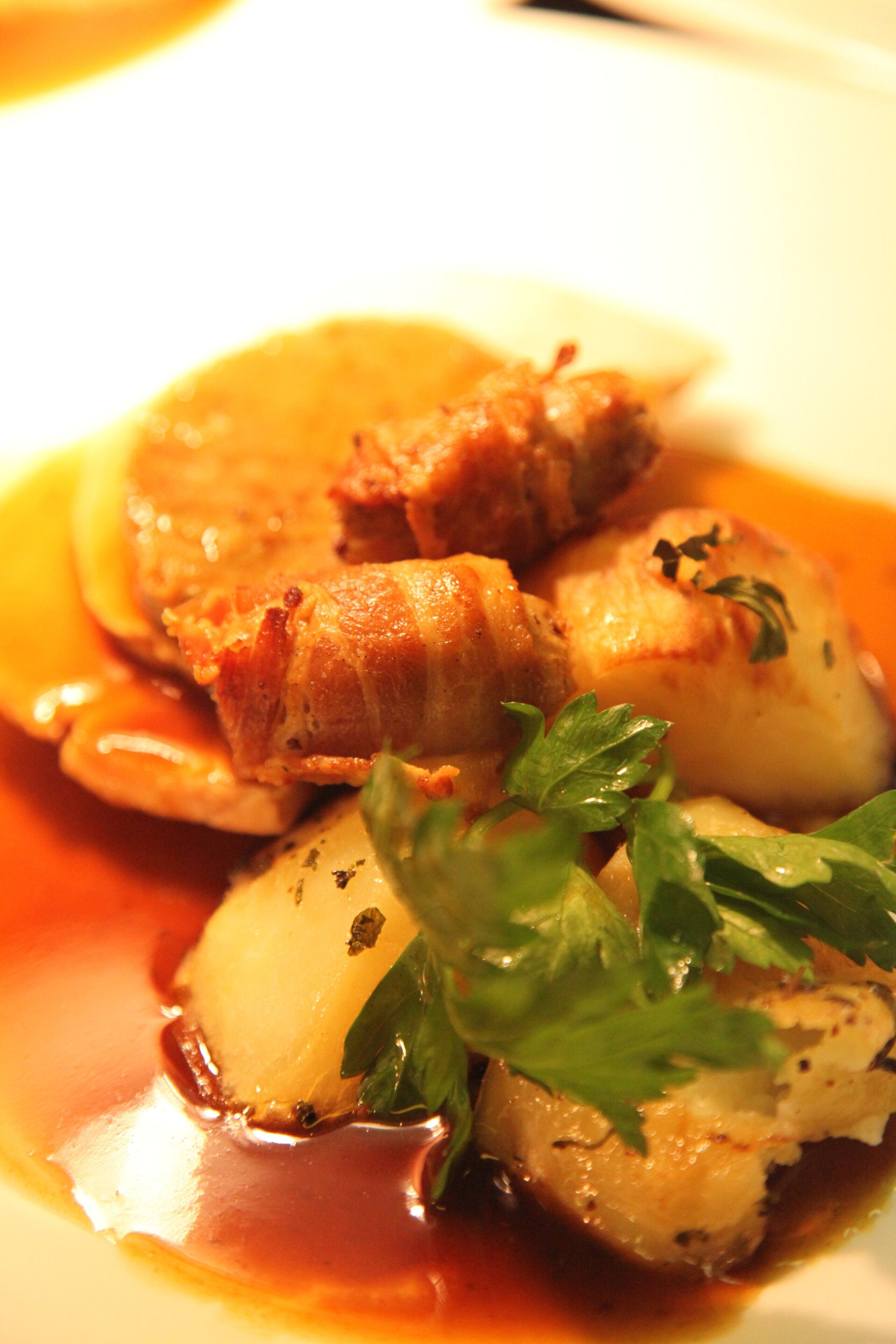 A plate with a dish that includes meat, potatoes, and a garnish.